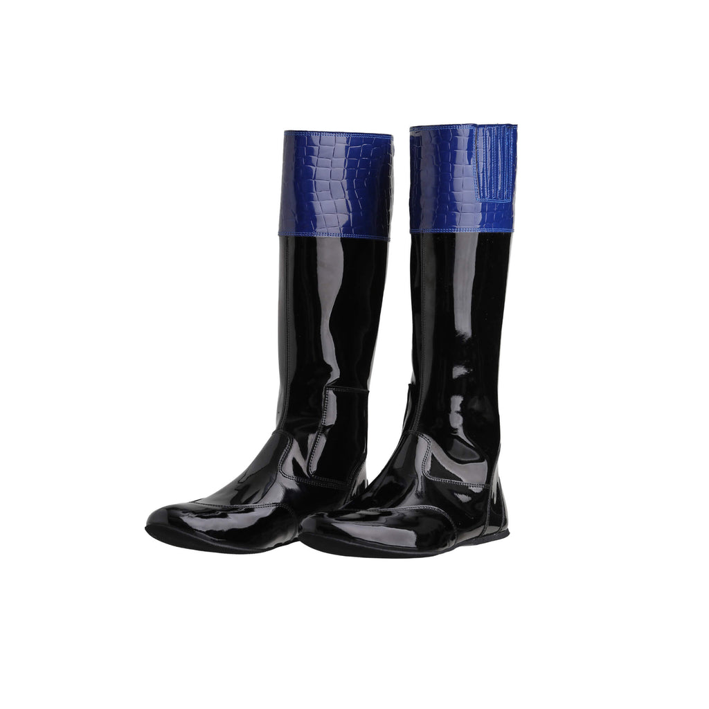 A pair of tall racing boots against a white background. The boots are made of black material with blue crocodile accents around the calf area. They feature a back zip and a 1.5-2cm stretch feature around the calf. The boots are crafted from light, tough, flexible, and strong material. Both shoes are positioned sole down with the zipper done, angled slightly to one side.
