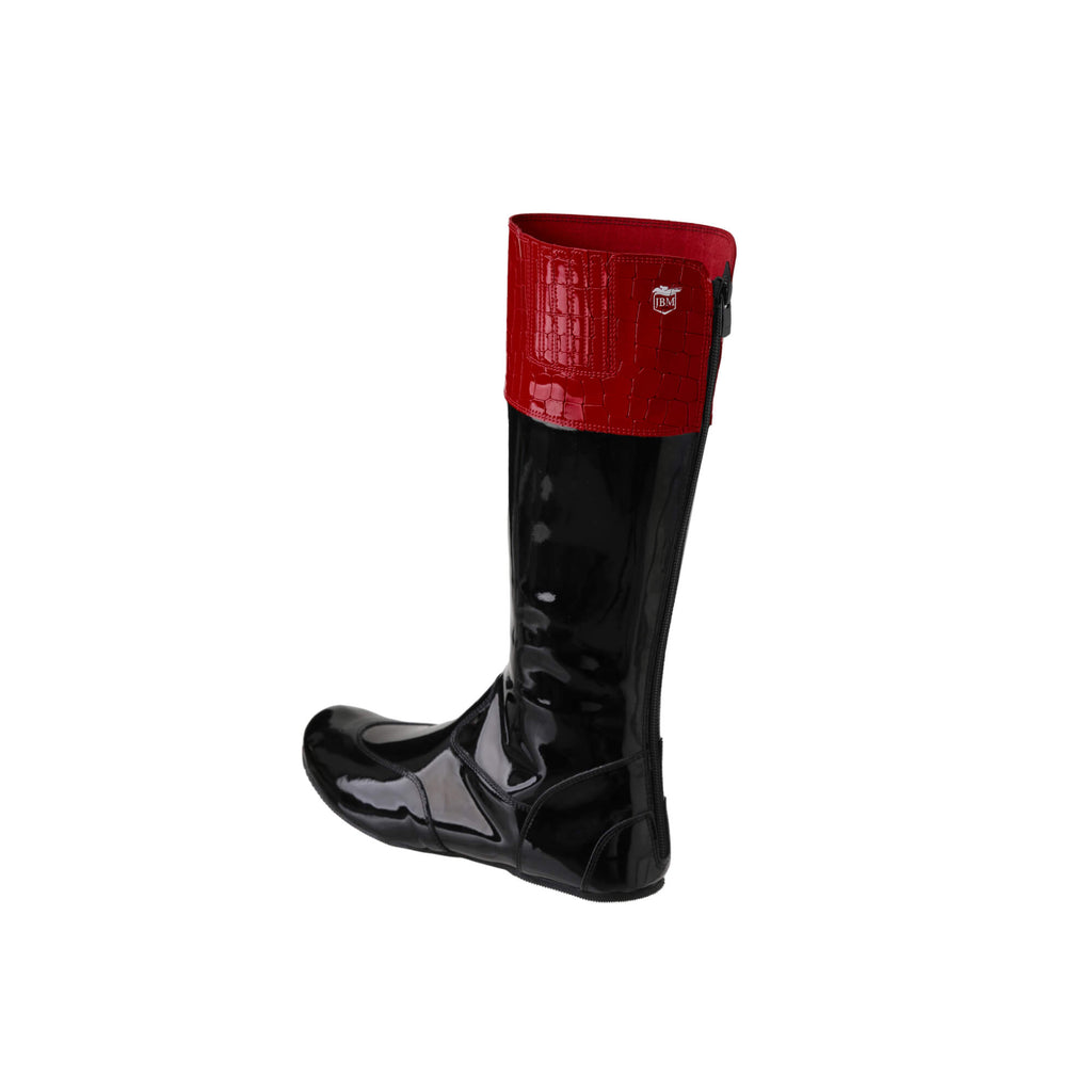 A  tall racing boot against a white background. The boot is made of black material with red crocodile accents around the calf. It features a back zip and a 1.5-2cm stretch feature around the calf. This image showcases one boot from a side-back perspective.