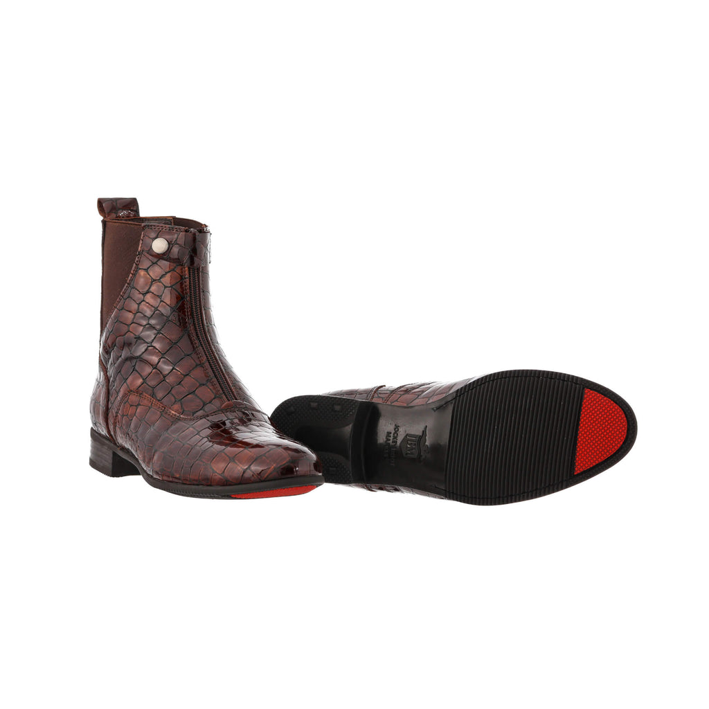 A pair of brown crocodile boots displayed against a white background. One boot is positioned sole-down with the front zip and buckle closure done. The other boot is laid flat to showcase its red-tipped sole design.