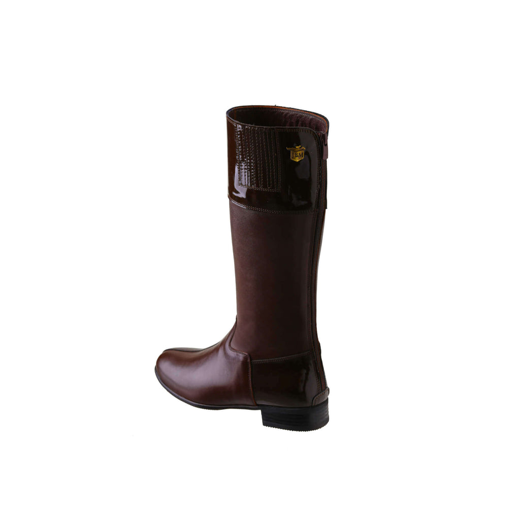 A single tall racing boot displayed against a white background. Made of brown leather with brown patent leather wrapping around the calf, it features a back zip and a 1.5-2cm stretch feature on the calf area. The boot is shown from a side-back perspective.